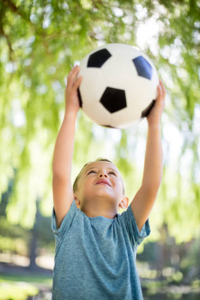 istock Boy playing with a football in park 656286702