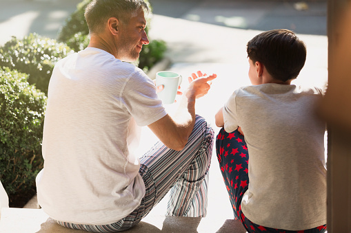 Father with coffee talking to son on front stoop