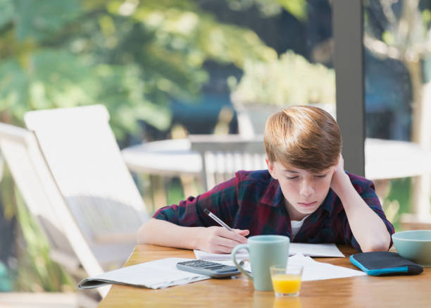 ダイニングテーブルで数学の宿題をしている男の子 - reading and writing ストックフォトと画像