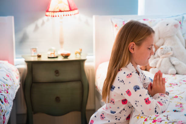 istock Girl in pajamas saying bedtime prayers at bed 656287341