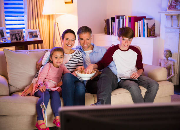 família comendo pipoca e assistindo tv na sala - family sofa night indoors - fotografias e filmes do acervo