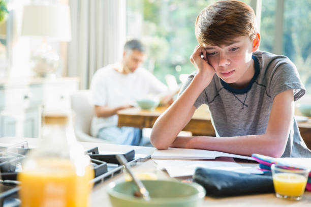 Frustrated boy doing homework at breakfast Frustrated boy doing homework at breakfast boring homework twelve stock pictures, royalty-free photos & images