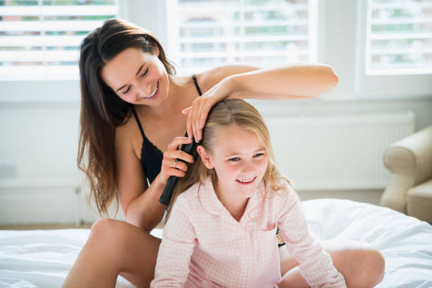 Mother brushing daughters hair on bed Mother brushing daughters hair on bed brushing hair stock pictures, royalty-free photos & images