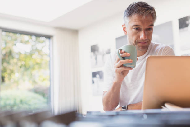 istock Man drinking coffee and working at laptop in kitchen 656287813