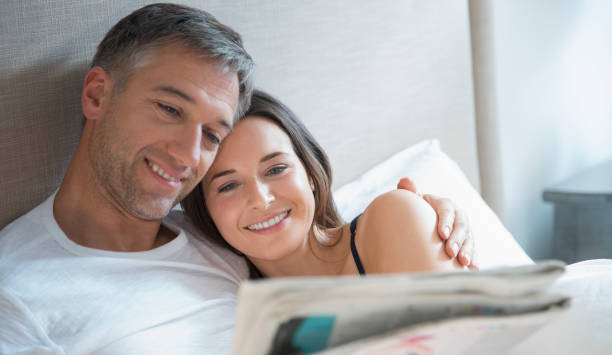 istock Smiling couple reading newspaper in bed 656287817