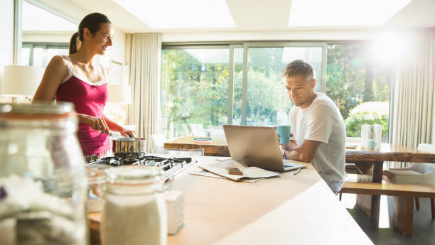 カップルの料理と朝のキッチンでラップトップで働く - convenience using laptop laptop people ストックフォトと画像