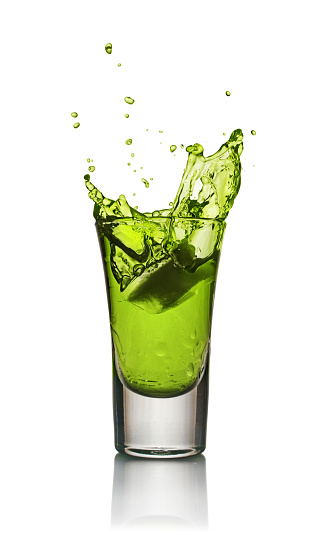 Glass of alcoholic drink with ice isolated on white background. Absinthe or mint liquor shot