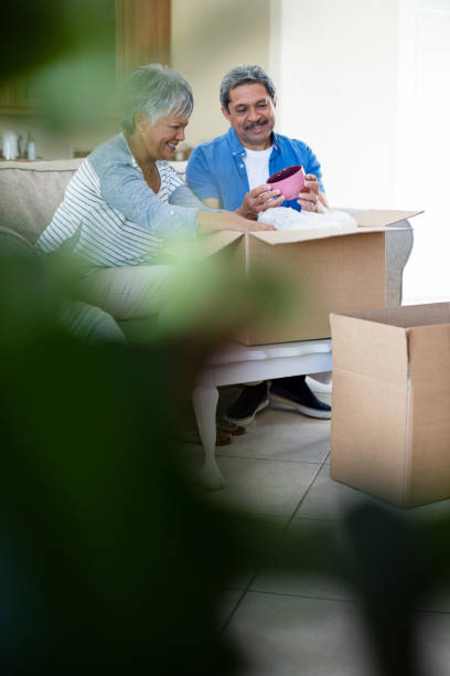 istock Senior couple unpackaging cardboard box in living room 656318536