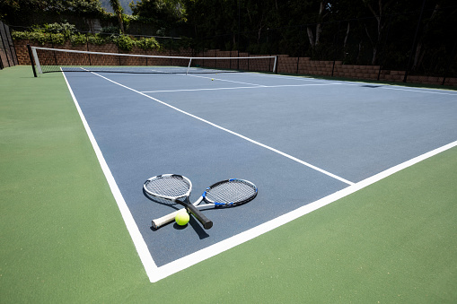 Tennis racquets and ball in court on a sunny day