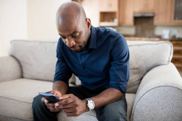 istock Man using mobile phone in living room 656319728