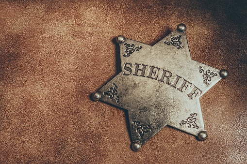 Sheriff badge on brown leather texture background. Macro shot.