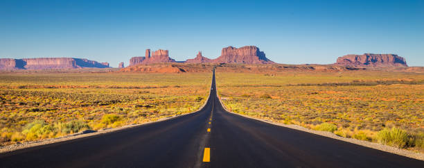 Monument Valley with U.S. Highway 163 at sunset, Utah, USA Classic panorama view of historic U.S. Route 163 running through famous Monument Valley in beautiful golden evening light at sunset on a beautiful sunny day with blue sky in summer, Utah, USA monument valley stock pictures, royalty-free photos & images
