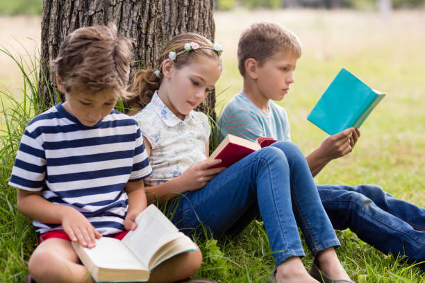 istock Kids reading books in park 656329644