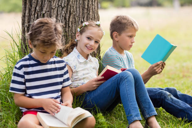 istock Kids reading books in park 656329650