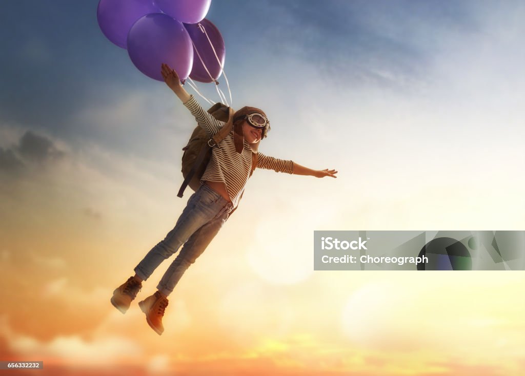 Child flying on balloons Dreams of travel! Child flying on balloons against the backdrop of a sunset. Child Stock Photo