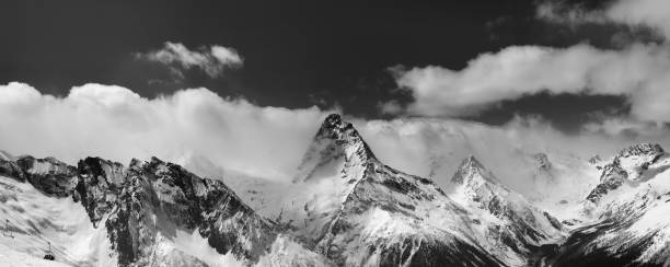 istock Black and white panorama of snowy mountains in clouds 656339552