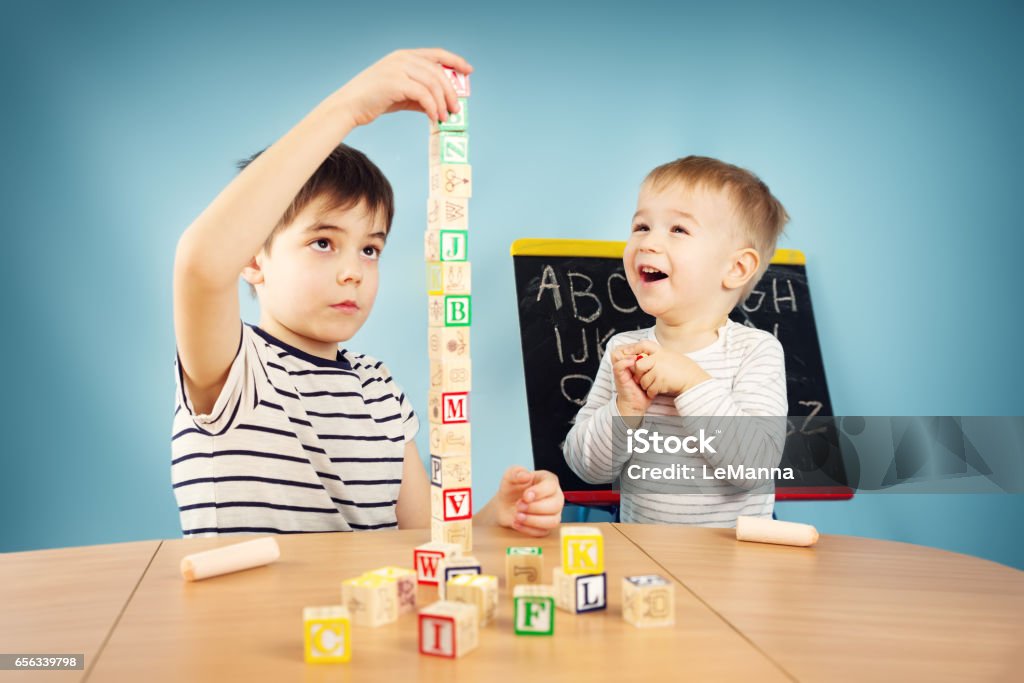 Children playing with cubes on the table Children playing with cubes on the table. Boys studying letters Child Stock Photo