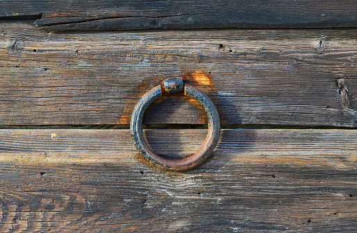 Image of two rusted iron rings from a guardrail on a bridge in Western Massachusetts, with focus on the foreground. The two rings create a unique frame for the calm stream and lush green trees in the background.