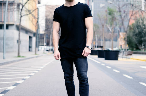 young muscular man wearing black tshirt and jeans posing on the street of the modern city. blurred background. hotizontal mockup. - hotizontal imagens e fotografias de stock