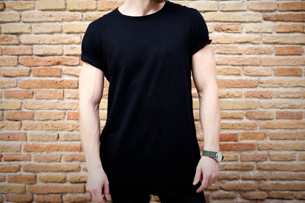 closeup view of young muscular man wearing black tshirt and jeans posing outside. empty brown grunge brick wall on the background. hotizontal mockup. - hotizontal imagens e fotografias de stock