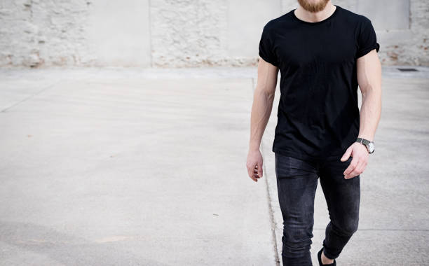 jungen muskulösen mann tragen schwarze t-shirt und jeans, die zu fuß auf den stadtteil. der hintergrund jedoch unscharf. hotizontal mock-up. - hotizontal stock-fotos und bilder