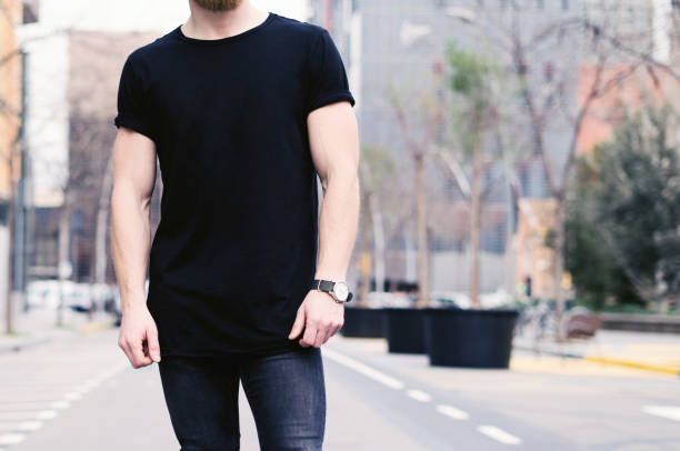 closeup view of young muscular man wearing black tshirt and jeans posing on the street of the modern city. blurred background. hotizontal mockup. - hotizontal imagens e fotografias de stock