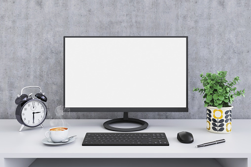 Large PC computer monitor on a business office white desk, gray wall in the background, lamp, green plant, coffee cup, keyboard, decoration and details, accessories, blank screen for copy space. designer direct view template