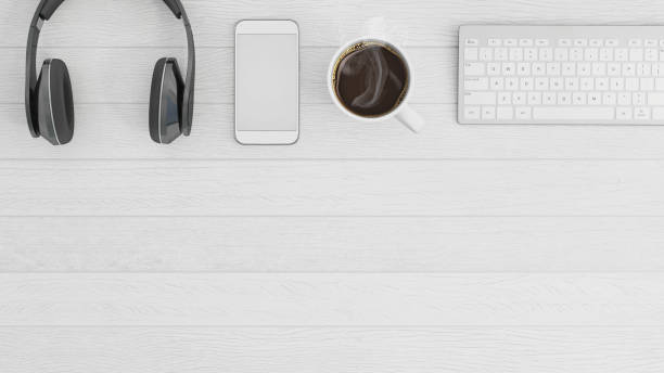 Business knolling designer overhead office desk view,white wood desk, headphones, keyboard, coffee cup, tablet screen, large tablet, pencils, laptop,  smartphone with a blank screen. designer copy space. horizontal composition. No people template mock up