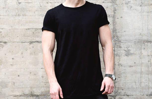 closeup view of young muscular man wearing black tshirt and jeans posing in center of modern city. empty concrete wall on the background. hotizontal mockup. - hotizontal imagens e fotografias de stock