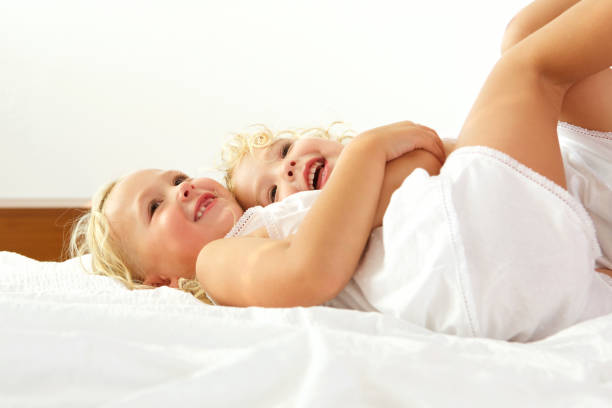 Close up portrait of two beautiful little girls lying together on bed