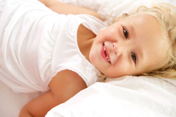 Close up portrait of beautiful little girl lying on bed