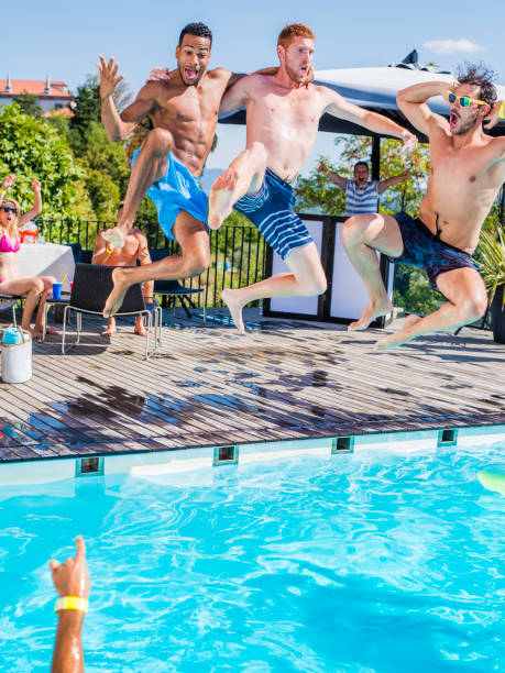 istock Three young men in swimming shorts jumping into pool 656391452
