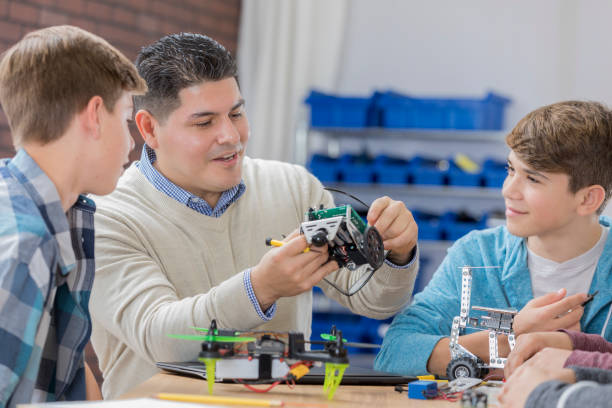 istock Cheerful teacher helps male students in technology class 656396222
