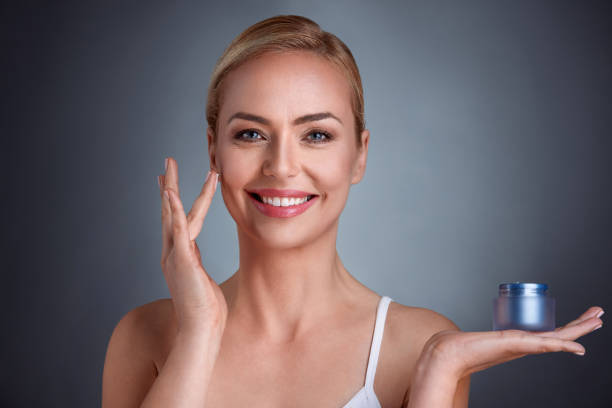 istock Smiling woman applying cream on face 656421732