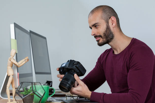 istock Photographer sitting at desk holding camera 656431660