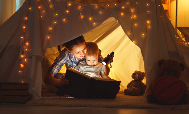 filha de mãe e filho com um livro e uma lanterna antes de ir para a cama - baby cheerful child blanket - fotografias e filmes do acervo