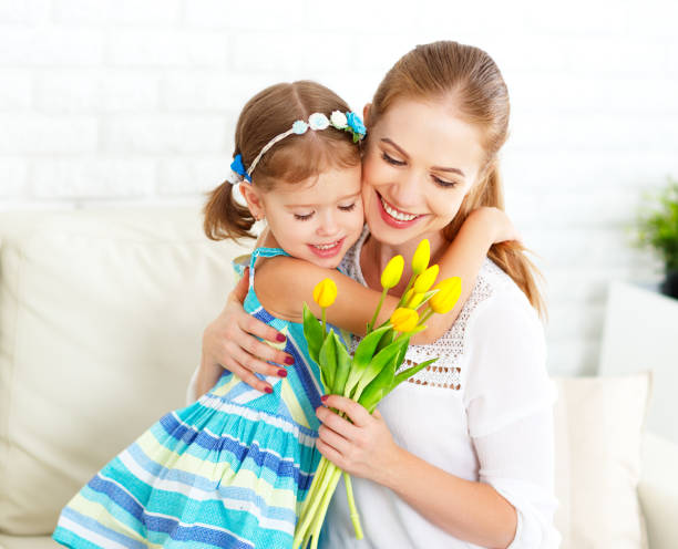 feliz dia das mães! a filha da criança felicua mamãs e dá-lhe um cartão e flores - birthday present family facial expression birthday - fotografias e filmes do acervo