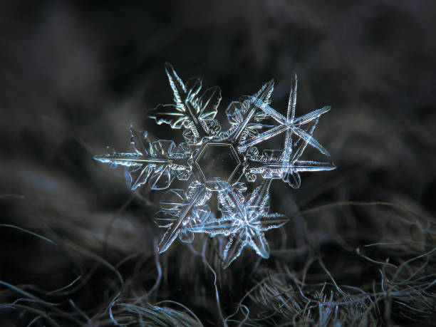 istock Cluster of three snowflakes glitters on dark gray textured background 656456338