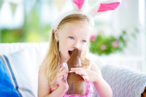 istock Cute little girl wearing bunny ears eating chocolate Easter rabbit 656479408