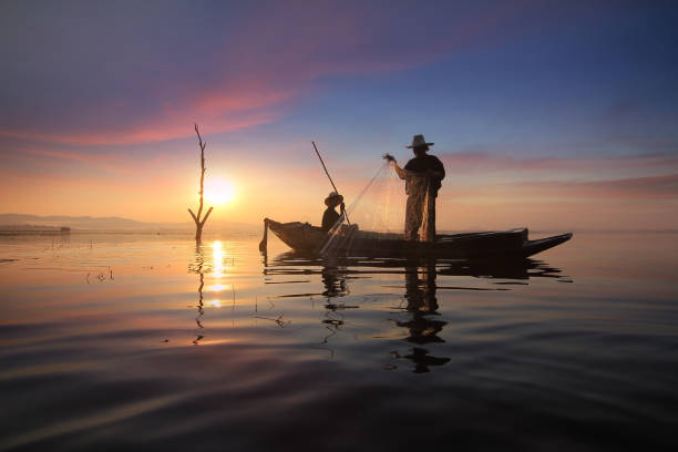 istock Silhouette of fishermen using nets to catch fish 656479596