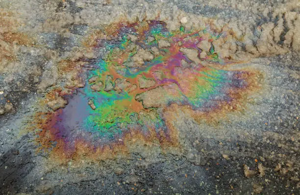 Puddled water polluted with fuel spill. gas spill in rainbow colors
