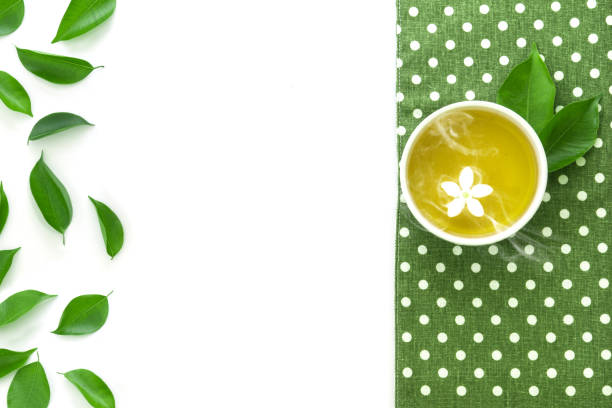 Top view shot of a hot cup of tea with green leaf decoration  with green napkin on white background , Organic green Tea ceremony time concept