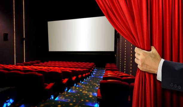 istock Cinema seats and blank screen with hand opening red curtain 656489884