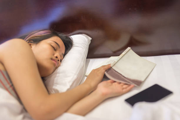 istock Young woman sleeping in bed with the book opened 656490502