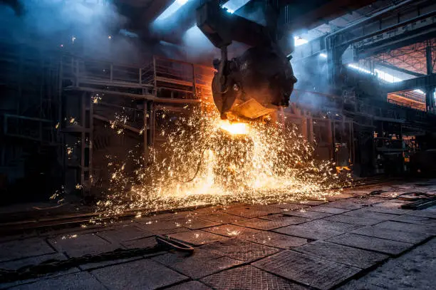 Pouring of liquid metal in open-hearth furnace. Production process in the steel mill. Working open hearth furnace.