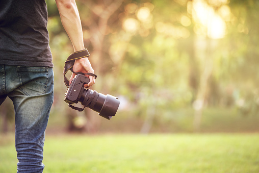 Man holding camera on walkway during his travel nature, copy space