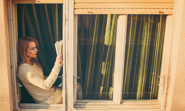 istock Woman reading book on sunny window at home 656508390