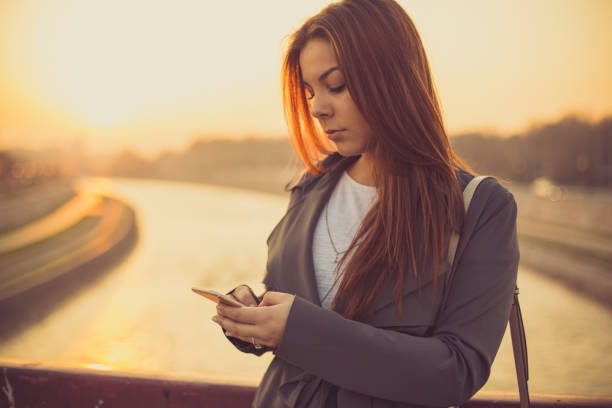 istock Beautiful girl using phone on the river bridge 656511432