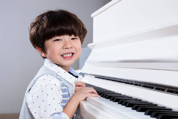 happy asian chinese little boy playing piano at home - practicing piano child playing imagens e fotografias de stock