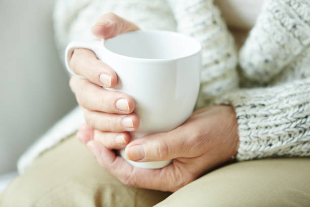 istock Wrinkled female hands holding cup of coffee 656516098